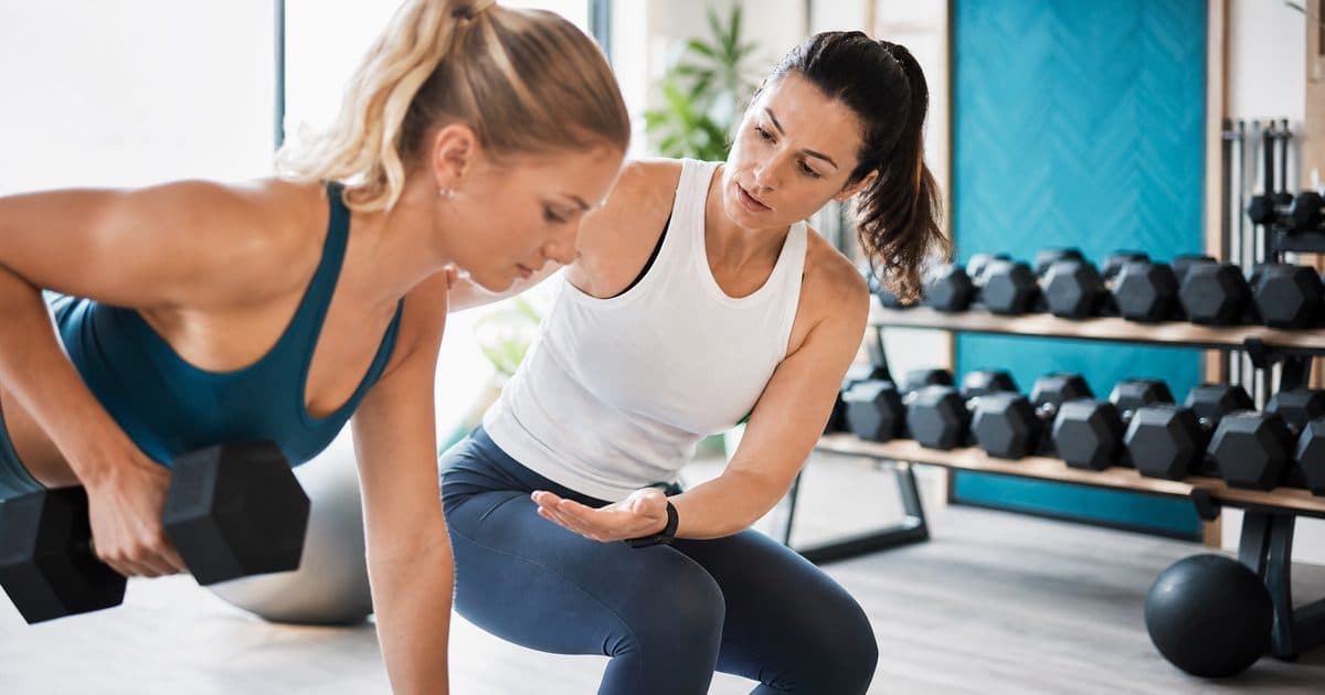 Boutique gym trainer giving a client personal attention to stand out from budget gyms
